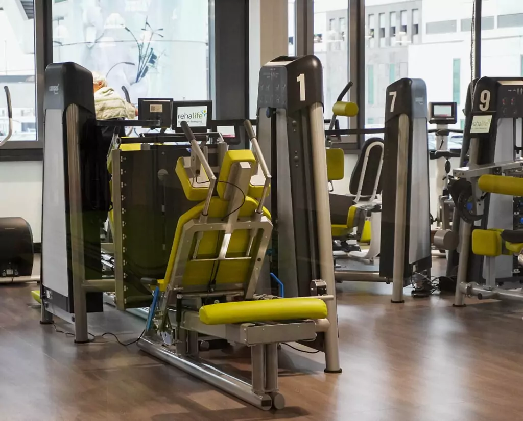 Ansicht einiger Geräte mit Gewichten, die an der Fensterfront des Kraftraums stehen.