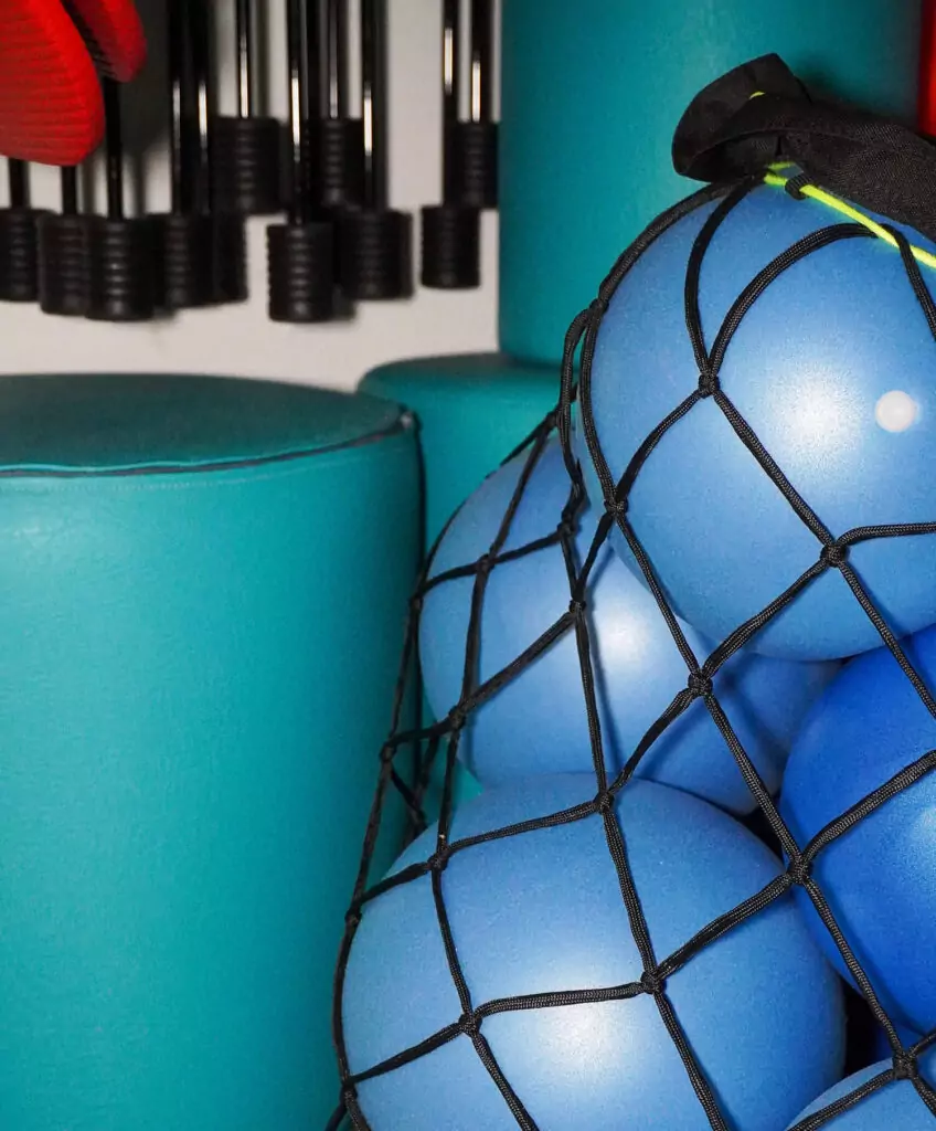 Nahaufnahme von einem Netz mit blauen Gummibällen und cyan-farbenden Rollen.